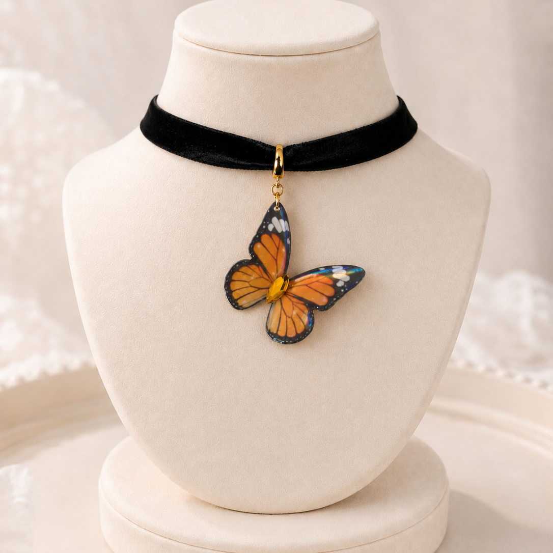 A black velvet choker necklace displayed on a cream jewelry bust, featuring a dangling butterfly charm with orange, blue, and black wings.