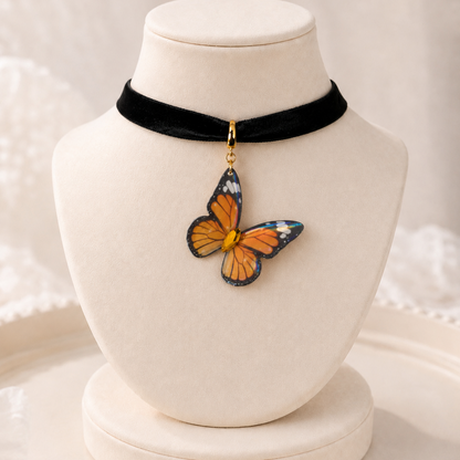 A black velvet choker necklace displayed on a cream jewelry bust, featuring a dangling butterfly charm with orange, blue, and black wings.